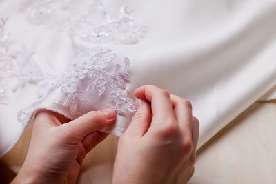 Cropped hands of woman stitching wedding dress