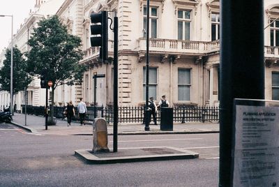 People on sidewalk by building in city