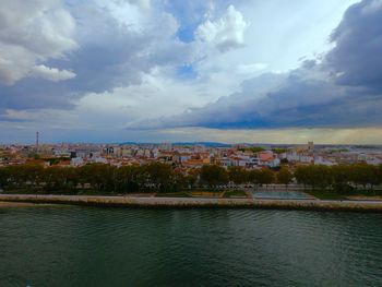 Scenic view of river by buildings in town against sky