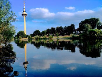 Reflection of trees on lake against sky in city