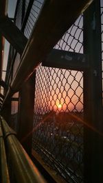 Close-up of metal fence against sky during sunset