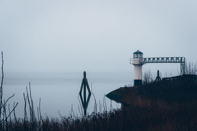 Lighthouse by sea against clear sky