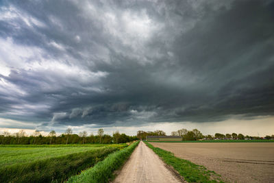 Road amidst field against sky