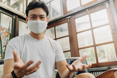 Midsection of man holding while sitting in window