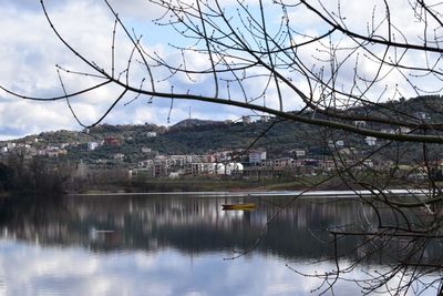 Reflection of trees in lake against sky in city