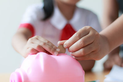 Cropped hand teaching girl to put coin