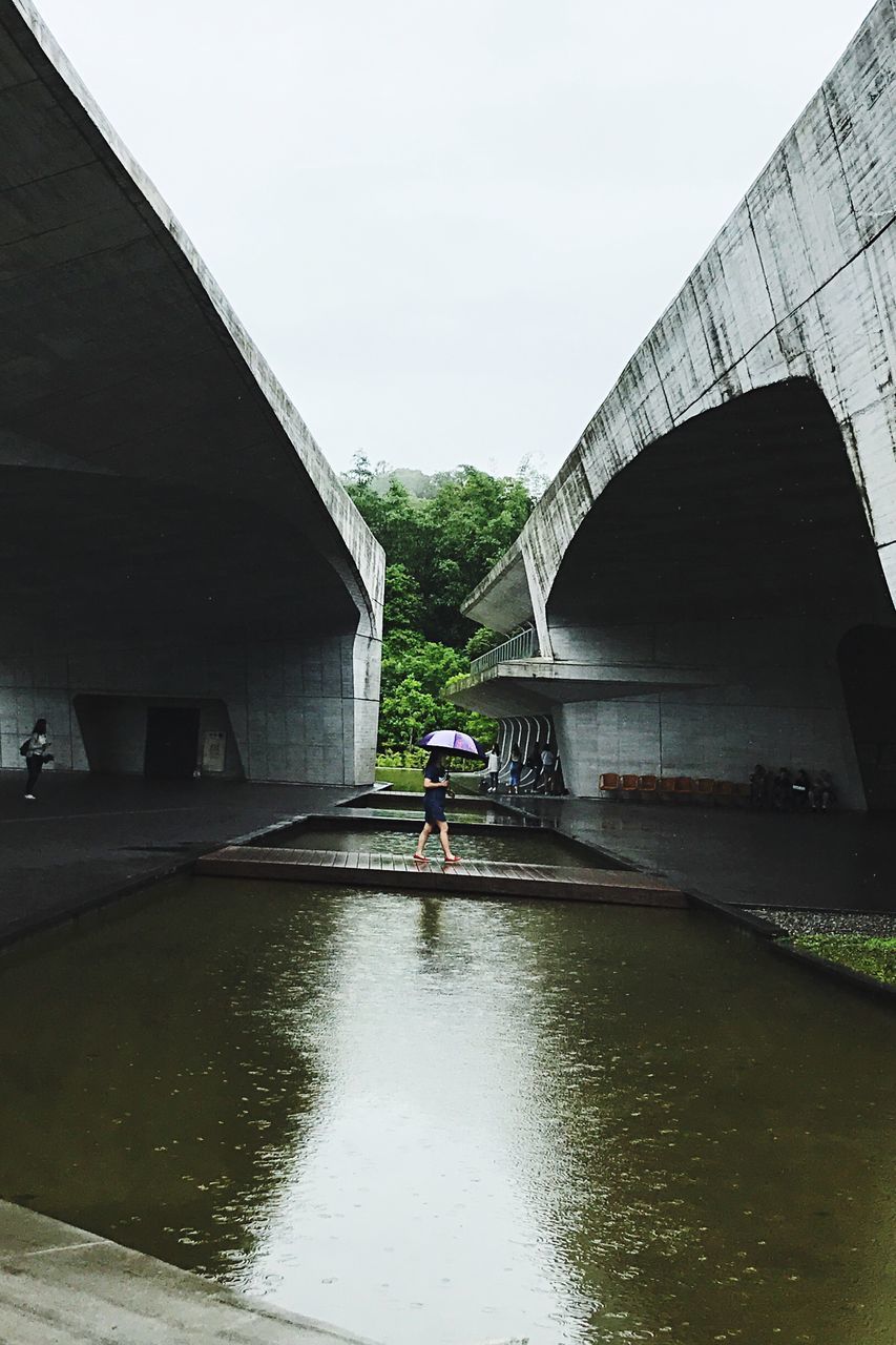 MAN BRIDGE OVER WATER AGAINST SKY