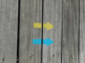 Close-up of arrow symbols on wooden fence