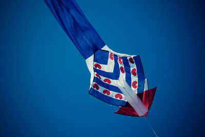 Low angle view of flag against clear blue sky