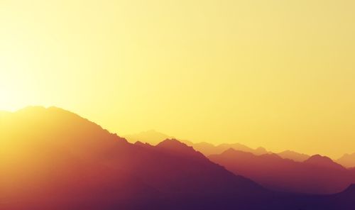 Scenic view of silhouette mountains against clear sky during sunset