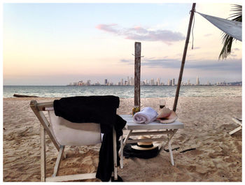 Chairs and table on beach against sky