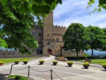 Trees by historic building against sky