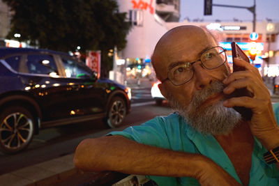 Side view of man using mobile phone while sitting on street