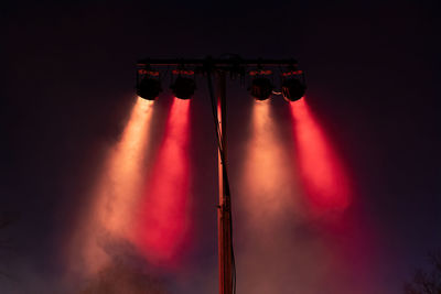 Low angle view of illuminated stage light against sky at night