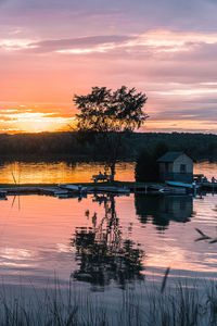 Silhouette tree by lake against romantic sky at sunset