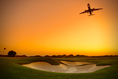 Airplane flying over land during sunset