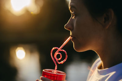 Close-up portrait of young woman drinking glasses outdoors