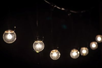 Illuminated light bulbs hanging in dark