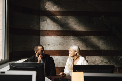 Business colleagues discussing while sitting at desk during meeting in office