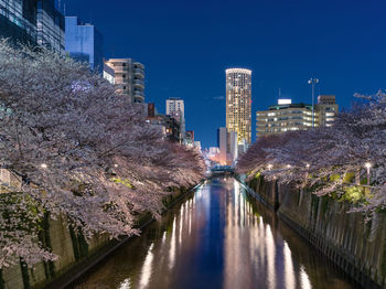 River amidst illuminated buildings against clear sky