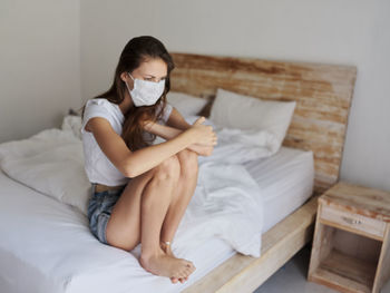 Young woman sitting on bed at home