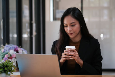 Young woman using mobile phone at table