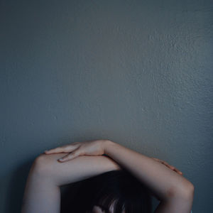 Midsection of woman sitting against wall