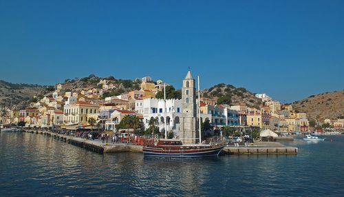 Sailboats in city against clear blue sky