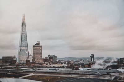View of cityscape against cloudy sky
