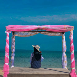 Rear view of woman with umbrella on beach against sky