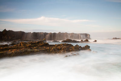 Scenic view of rocks in sea against sky