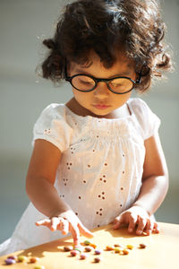 Cute girl playing with candy on table