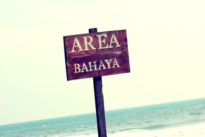 Information sign on beach against clear sky