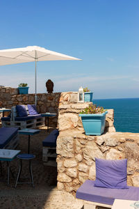 Chairs and table at beach against sky