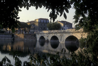 Arch bridge over river against buildings