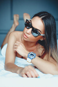 Close-up of young woman with sunglasses on bed