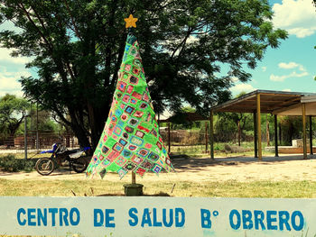 Information sign on tree by field against sky