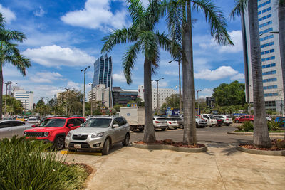 Cars on road by buildings against sky