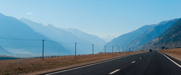 Road by mountains against sky