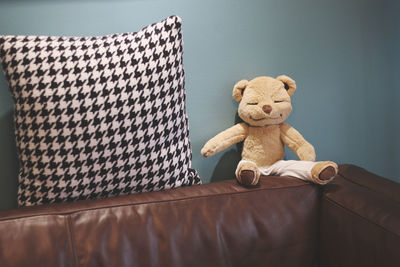Stuffed toy and cushion on sofa against wall at home