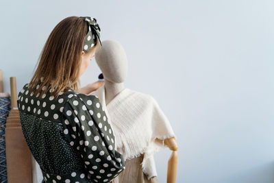 Rear view of woman standing by mannequin