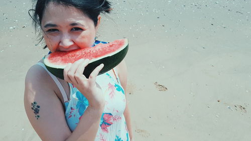 Portrait of woman eating watermelon at beach