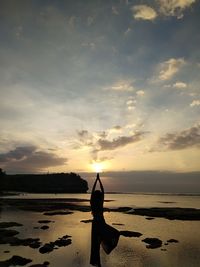 Silhouette woman at beach against sky during sunset