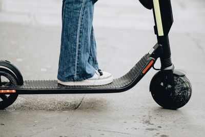 Low section of person with skateboard standing on street