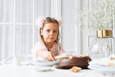 Funny girl with chocolate cake in hands on festive table at home. christmas time, birthday girl