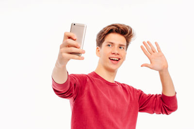 Portrait of smiling young man using mobile phone against white background