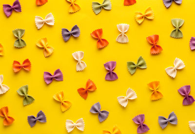 Directly above shot of uncooked bow tie pastas on yellow background