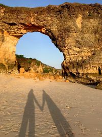 Shadow of holding hands couple againts arch rock formation