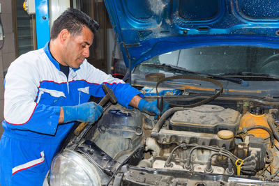 Mature mechanic repairing car