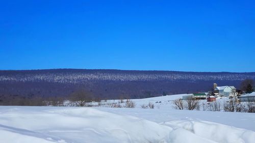 Scenic view of snowy field against clear blue sky